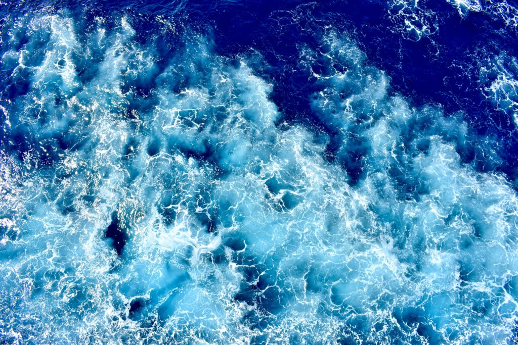 Dynamic aerial perspective of vibrant blue waves crashing in the ocean, exhibiting movement and energy.